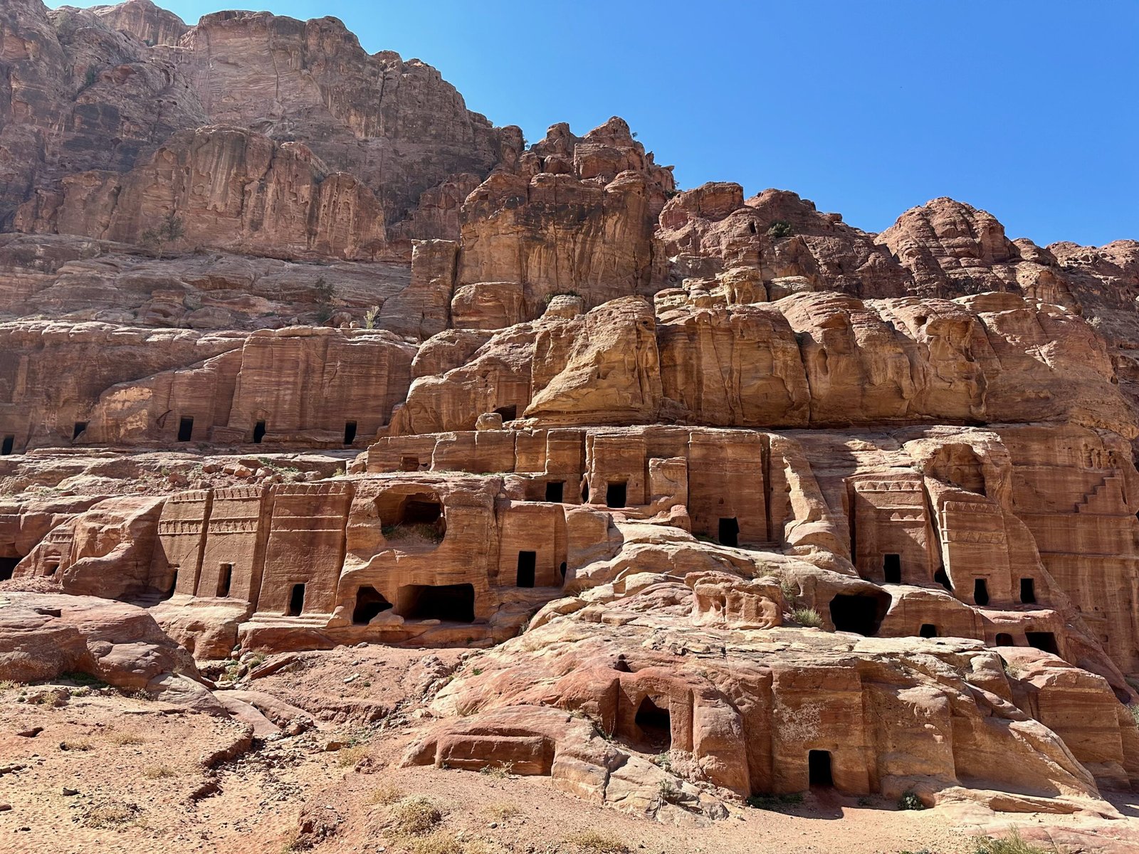 Numerous caves carved into the sandstone cliff wall at Petra.