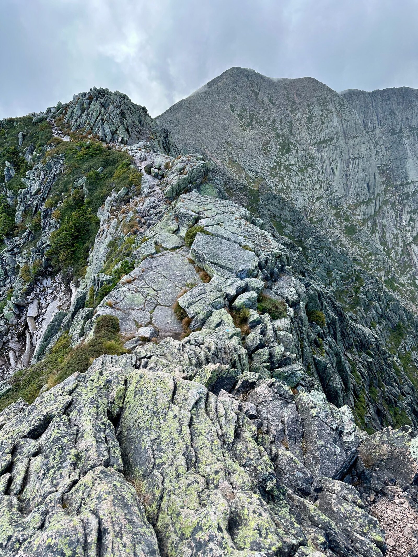 Knife Edge Trail on Mount Katahdin showing a narrow, rocky path with steep slopes on both sides, and the summit visible in the distance.