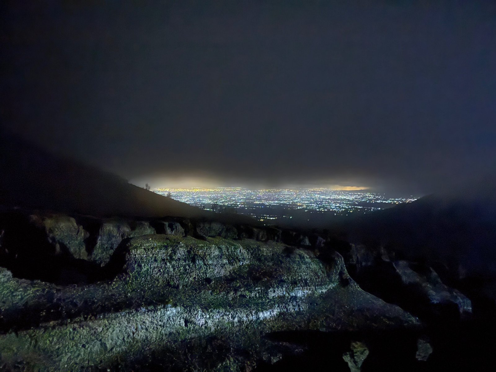 Nighttime view of Banyuwangi’s twinkling lights from the steep trail leading to the Ijen Volcano crater in East Java, Indonesia.