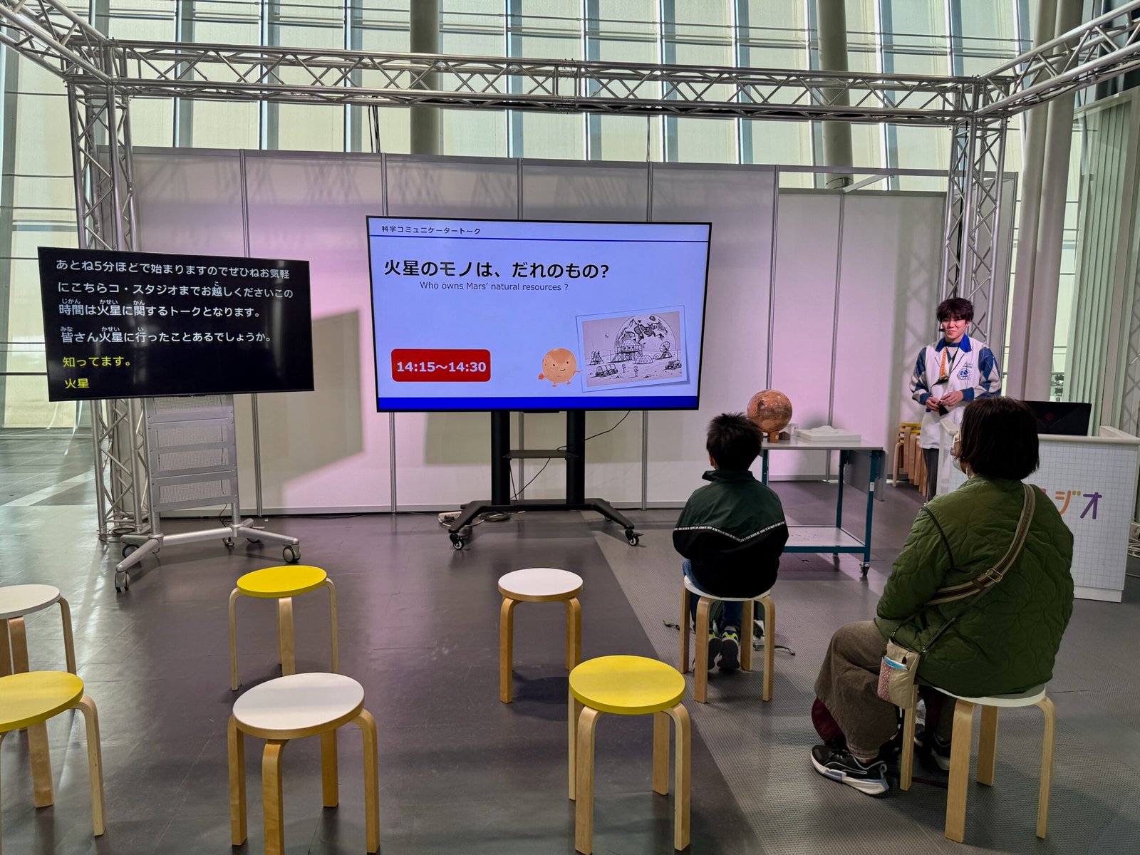 A presentation screen at Miraikan showing the topic “Who Owns Mars’ Natural Resources?” before the talk begins.