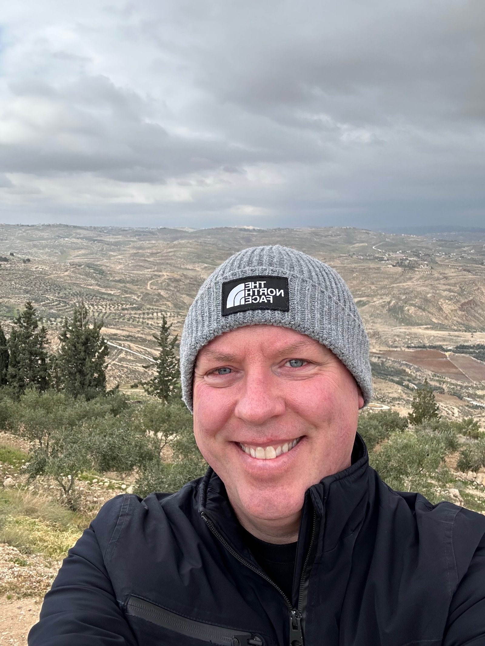 Don Trynor, author of the Curious Don website, standing at the summit of Mount Nebo with views of eastern Jordan and the Dead Sea.